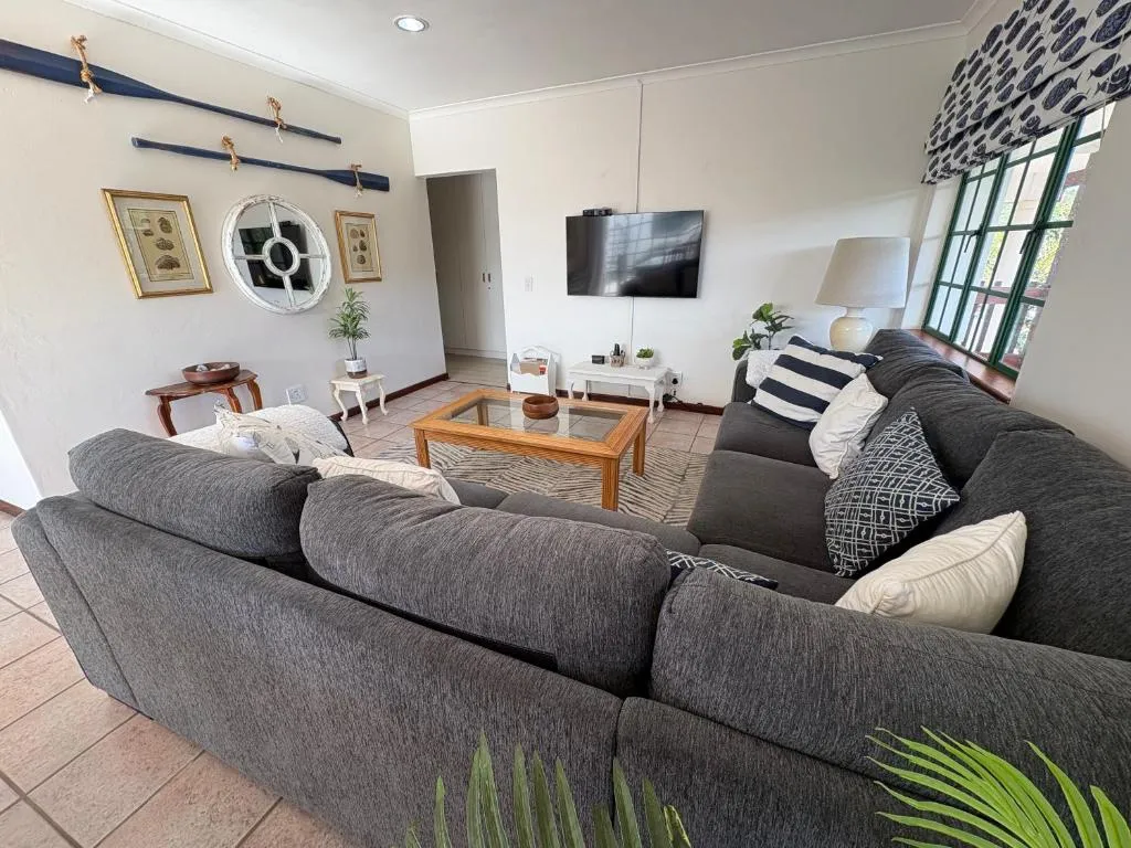 TV lounge with a grey corner sofa, wall-mounted television, and nautical oar decor