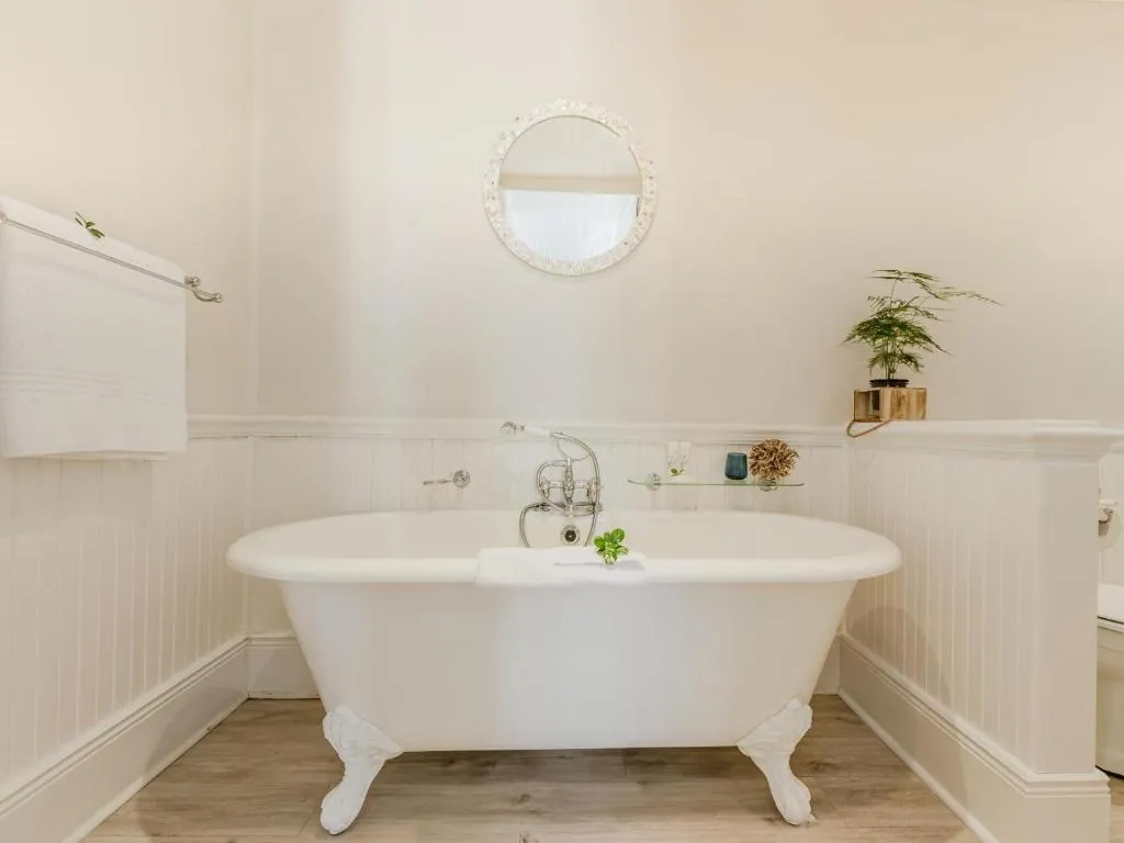 En-suite bathroom with a freestanding clawfoot bathtub and wainscot paneling
