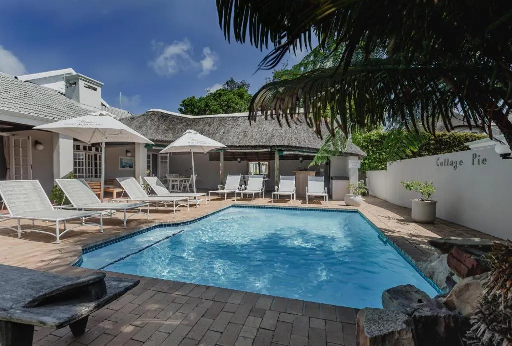 Swimming pool with sun loungers and a thatched lapa beside the Cottage Pie guest house