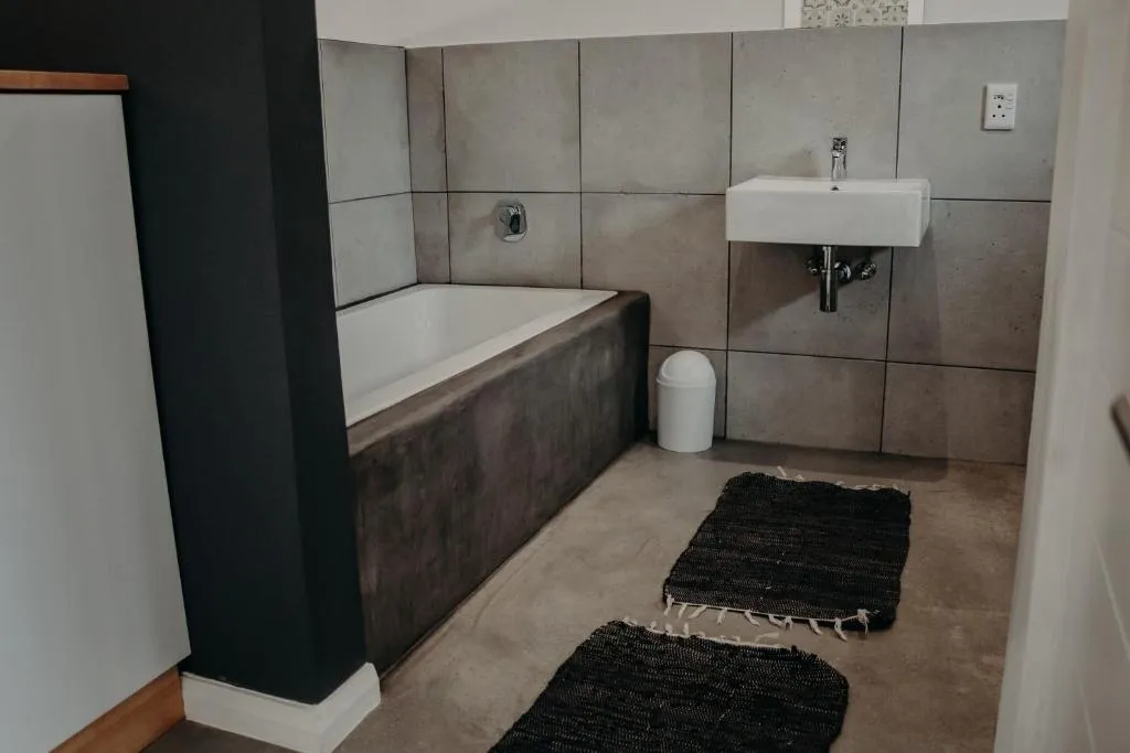 Bathroom with a built-in bathtub, concrete-tile walls and a wall-mounted basin