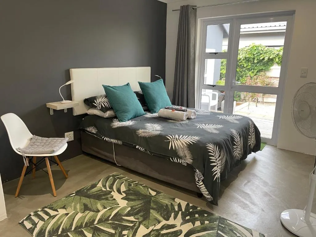 Bedroom with a charcoal accent wall and a glass door leading onto a small garden patio