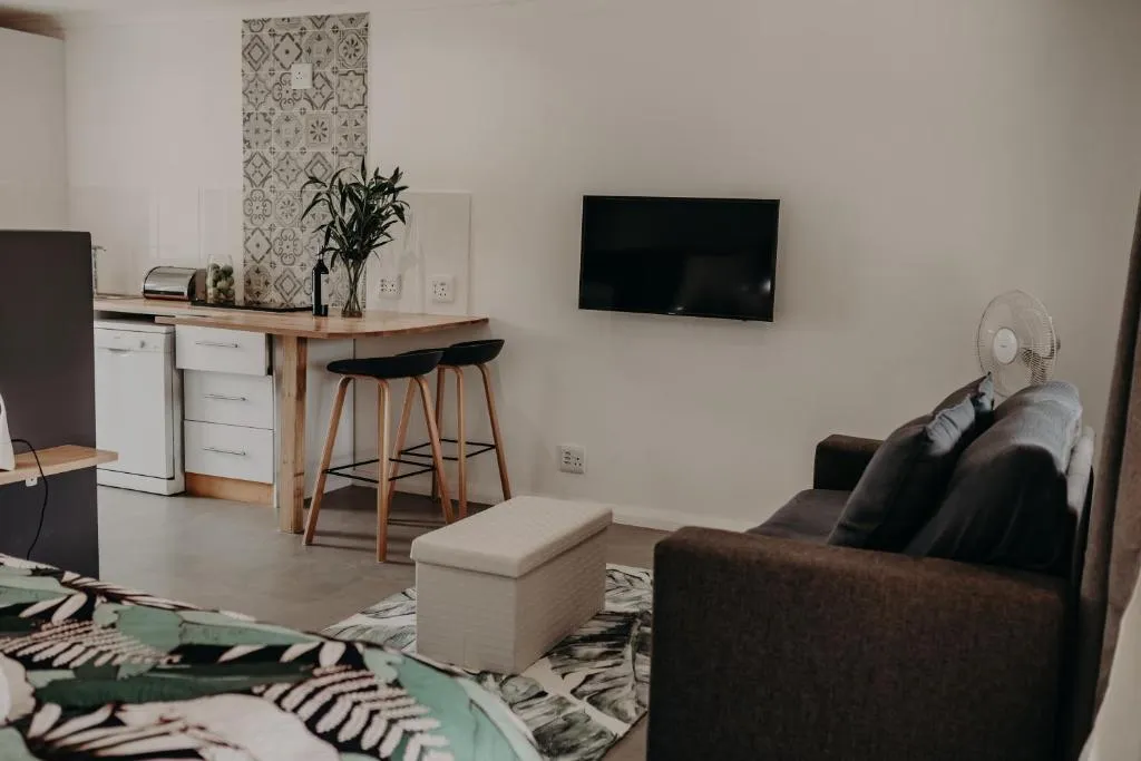 Living area with a wall-mounted TV, dark sofa and a breakfast bar beyond