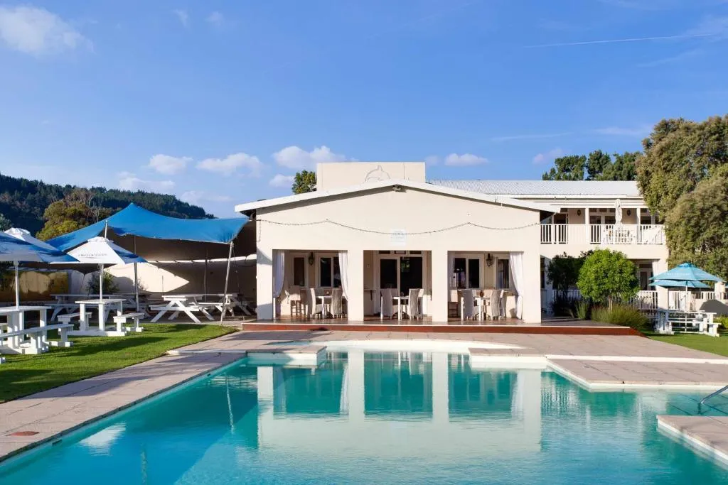 Shared complex pool terrace with picnic tables, umbrellas and a covered dining stoep