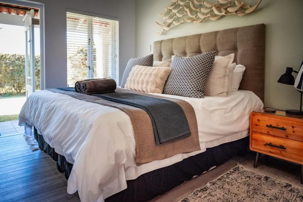 Bedroom with driftwood fish wall art above the headboard and French doors open to the garden