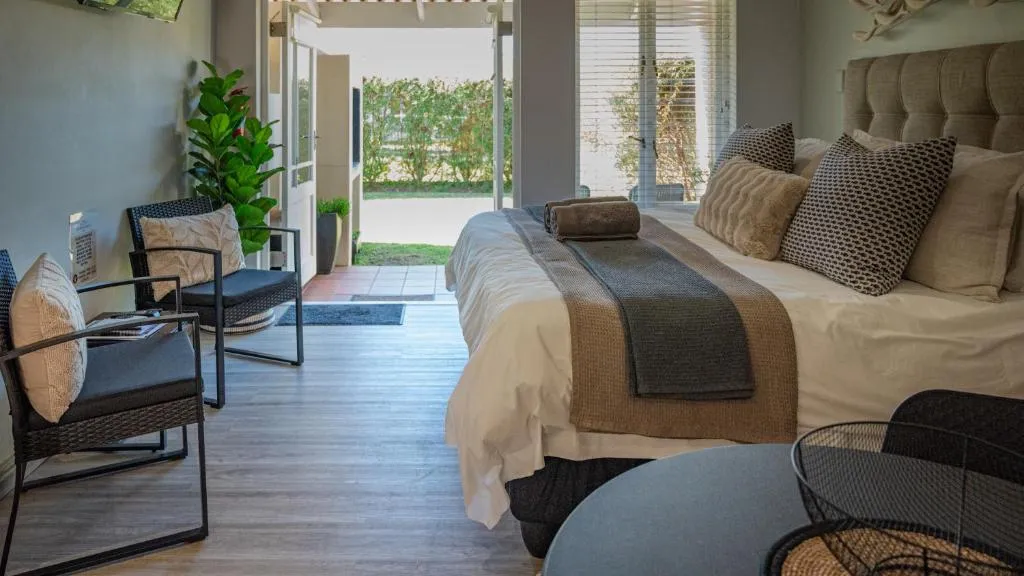 Open-plan studio with bed and lounge chairs facing French doors onto a small garden patio