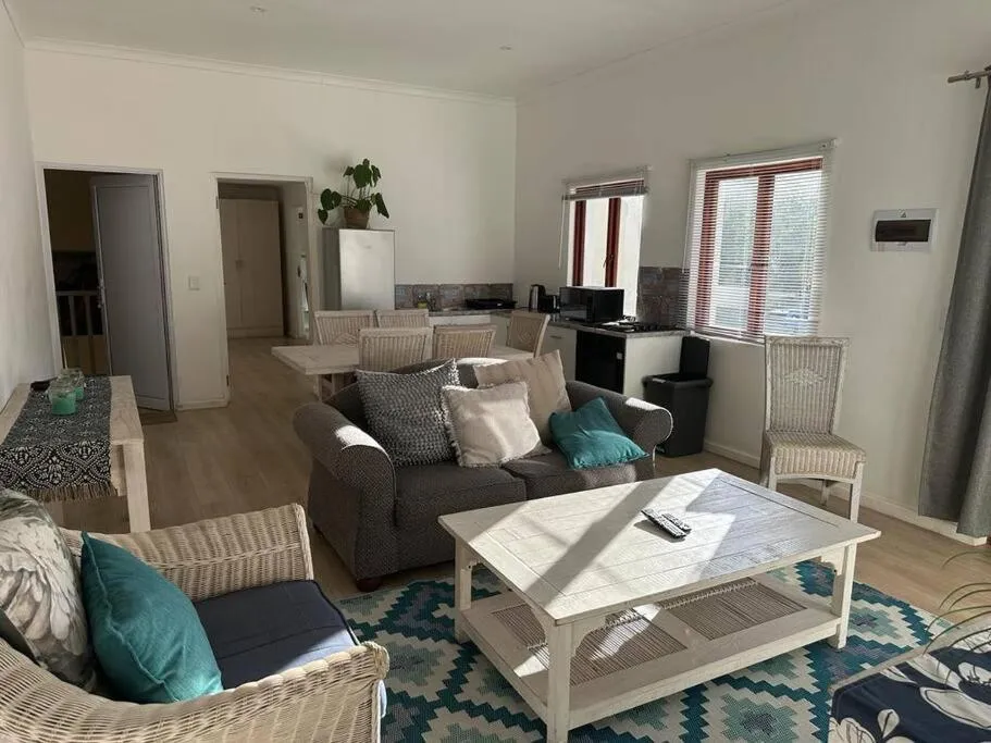 Open-plan lounge and kitchen with wicker armchairs, dining table and garden-facing windows