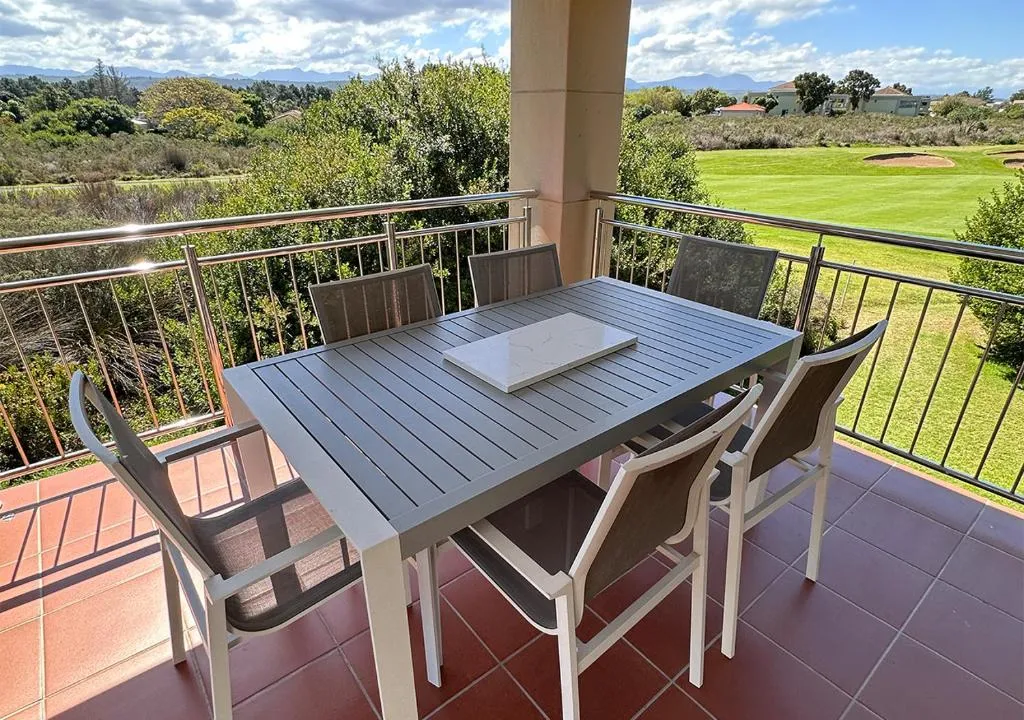 Balcony dining table for six overlooking the golf course fairway and mountains beyond