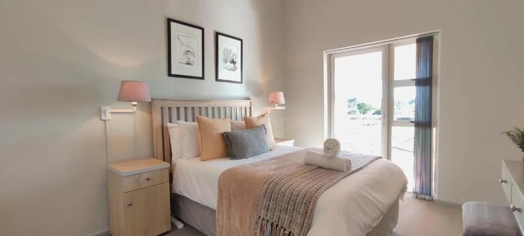 Bedroom with a wooden headboard, rolled towels and private balcony access