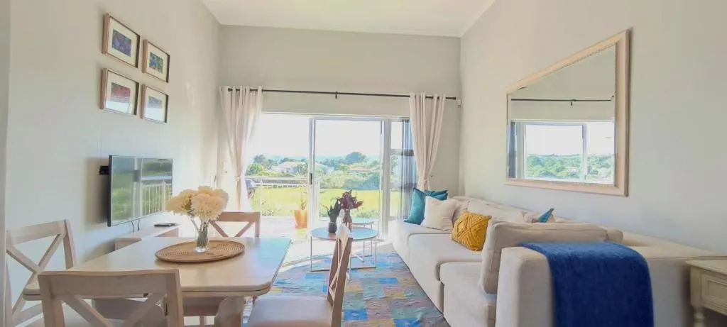 Open-plan living and dining area with sliding doors onto the balcony and golf view