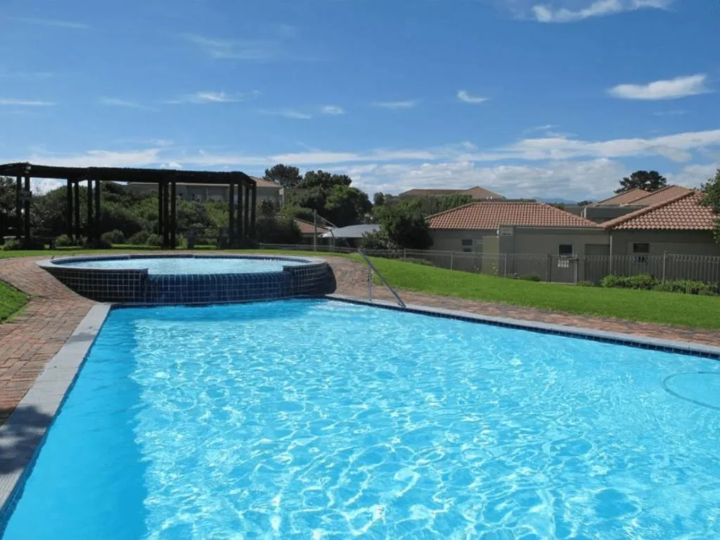 Communal swimming pool and spa with a timber pergola and estate homes beyond