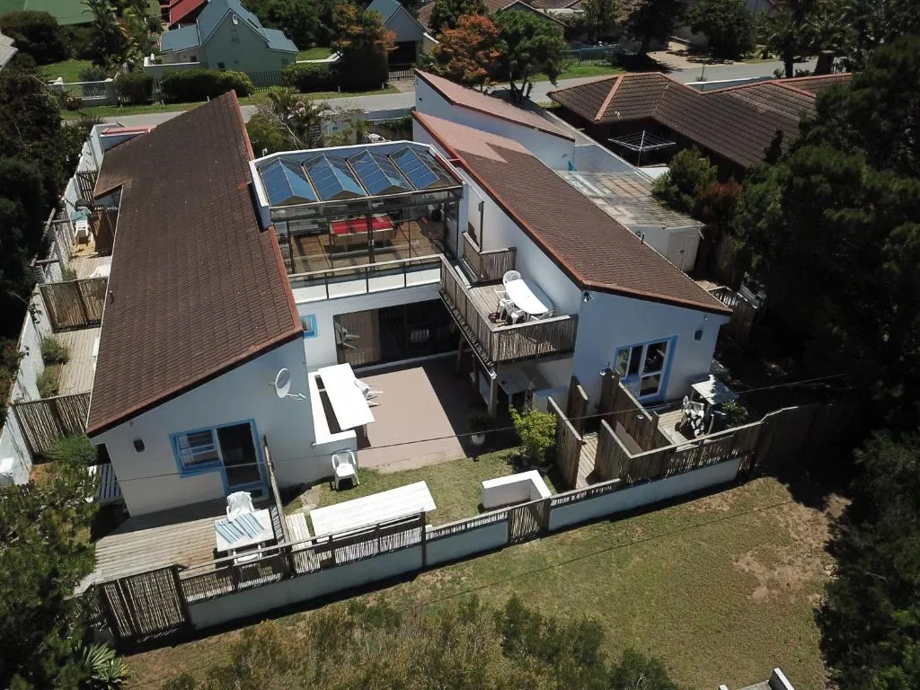 Aerial view of the property showing a glass-roofed upper sunroom, timber decks, and surrounding rooftops