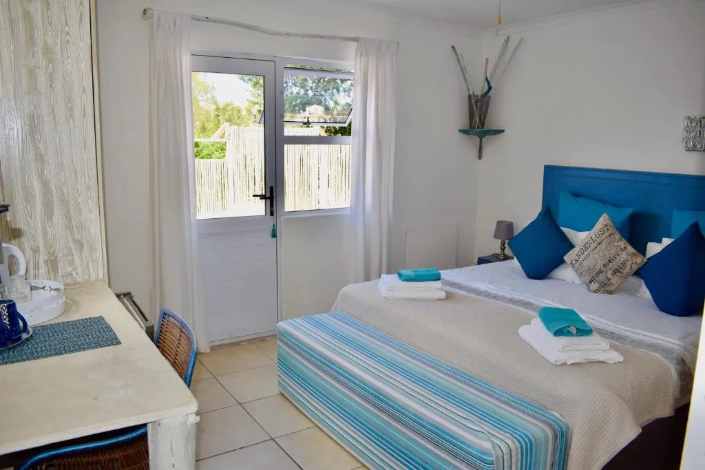 Bedroom with a blue headboard, teal striped throw, and a glass door onto a fenced patio