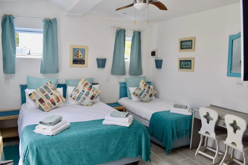 Twin bedroom with teal nautical decor, a double and a single bed, and a work desk