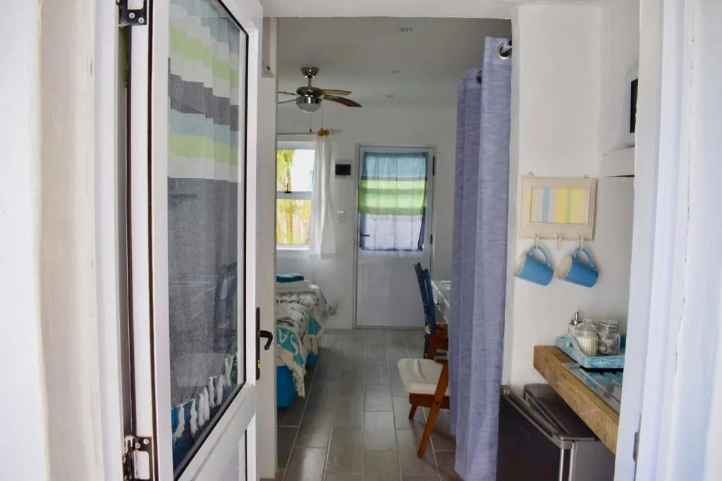 View through an open door along a corridor past a coffee station to a bedroom beyond