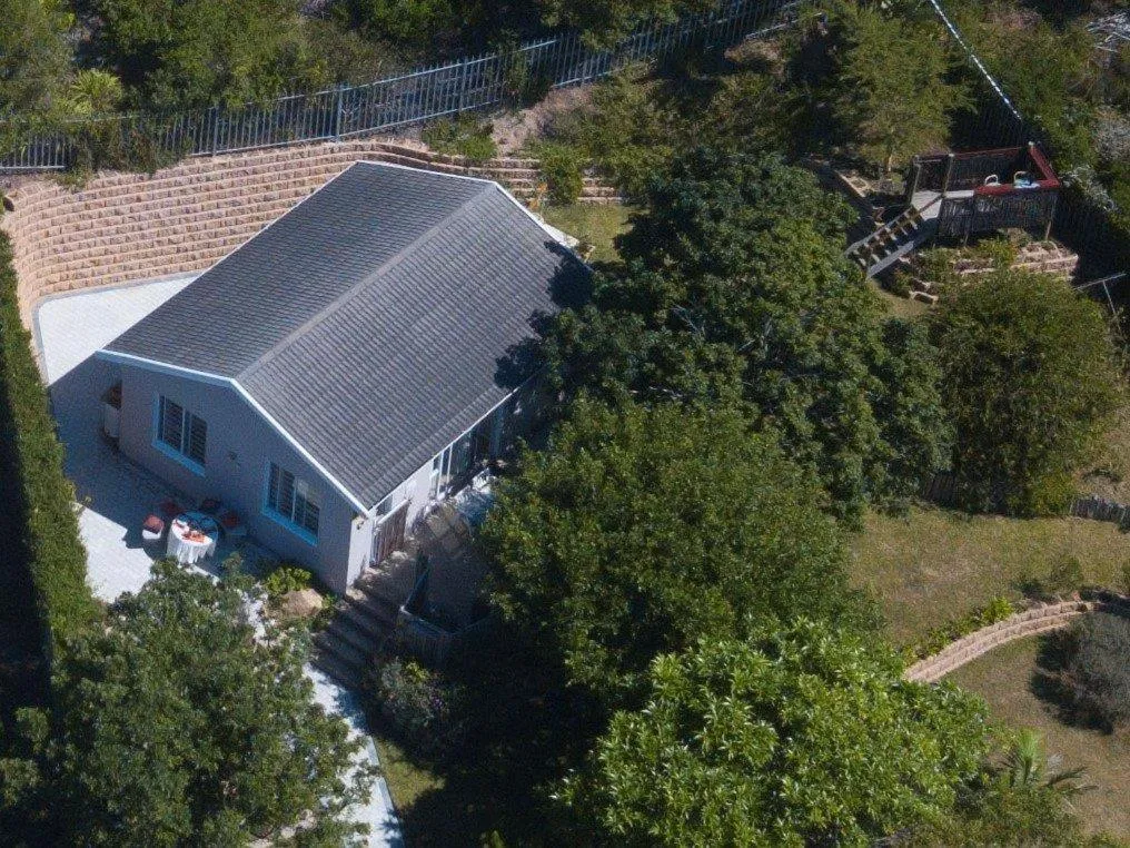 Aerial view of the house's pitched roof, patio, and terraced garden