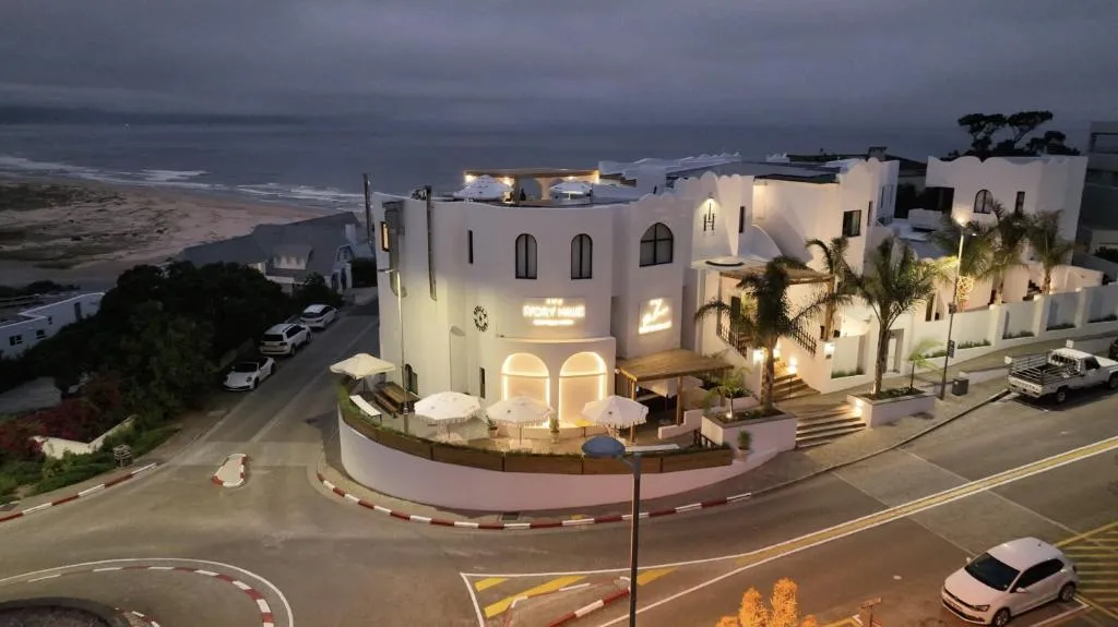 Aerial view of the hotel's white domed architecture lit up at night beside the beach