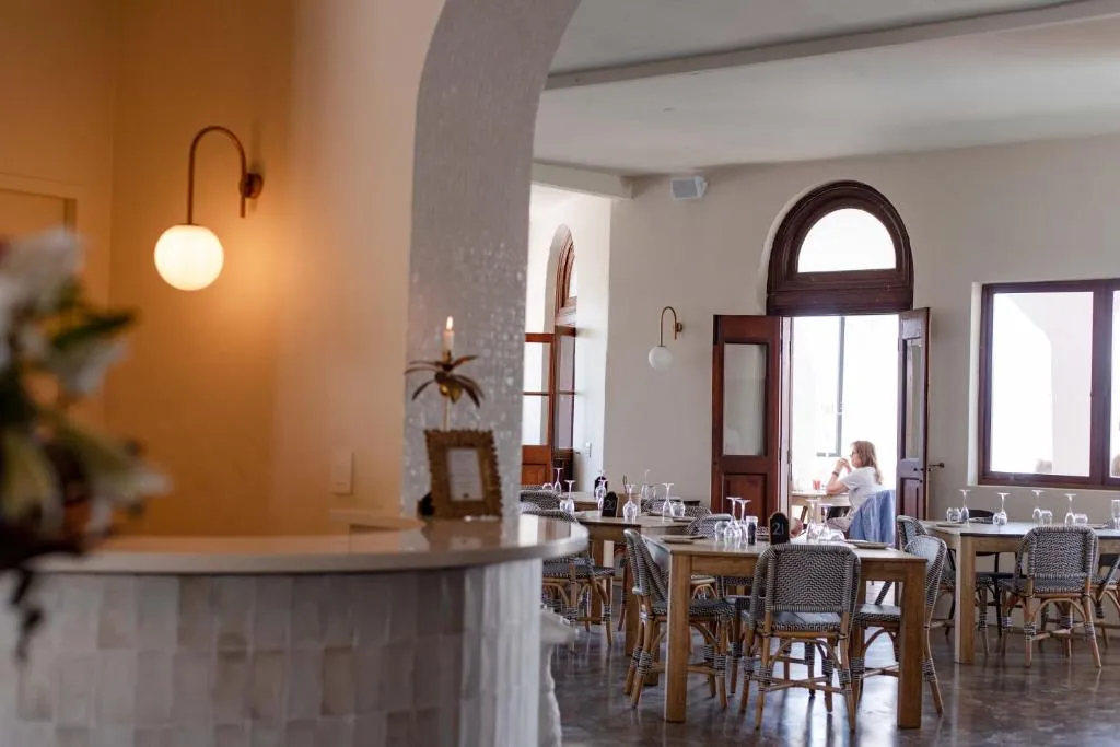 Restaurant dining room with wooden bistro chairs, arched doorways and a tiled bar counter