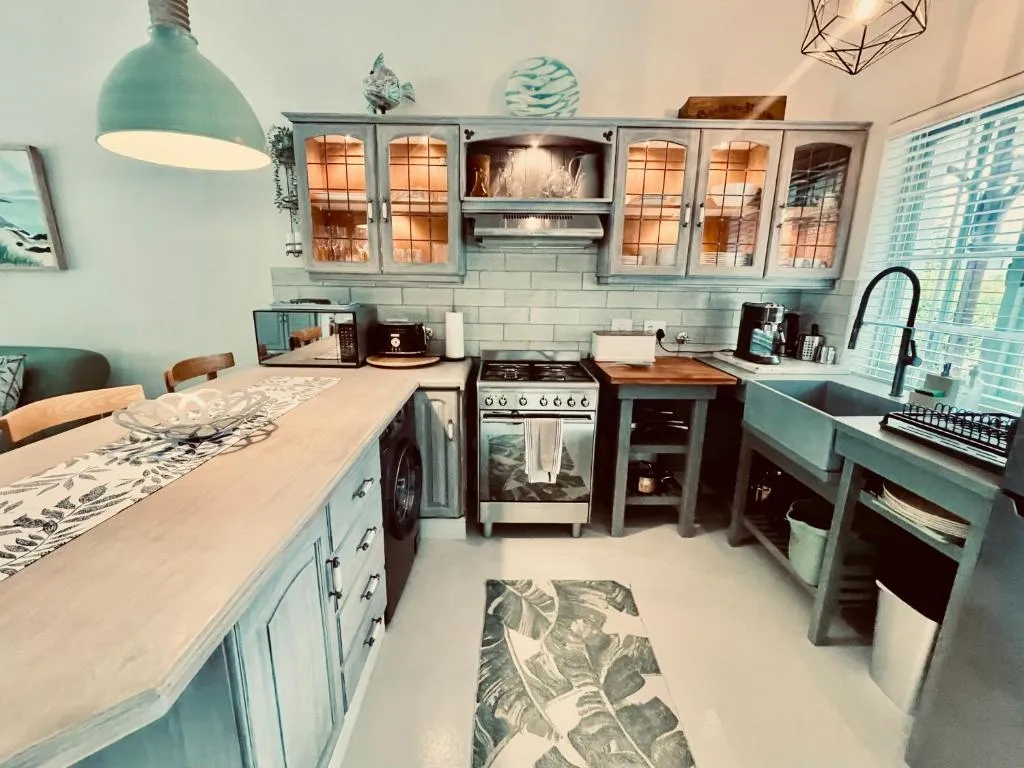 Teal farmhouse-style kitchen with an apron sink, gas stove and a banana-leaf runner rug