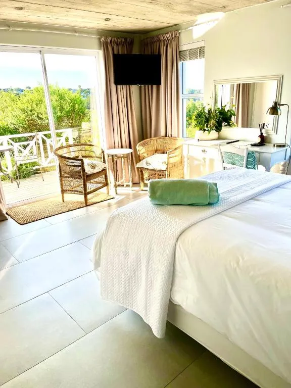 Bedroom opening onto a private deck with wicker chairs and a view over green hillside