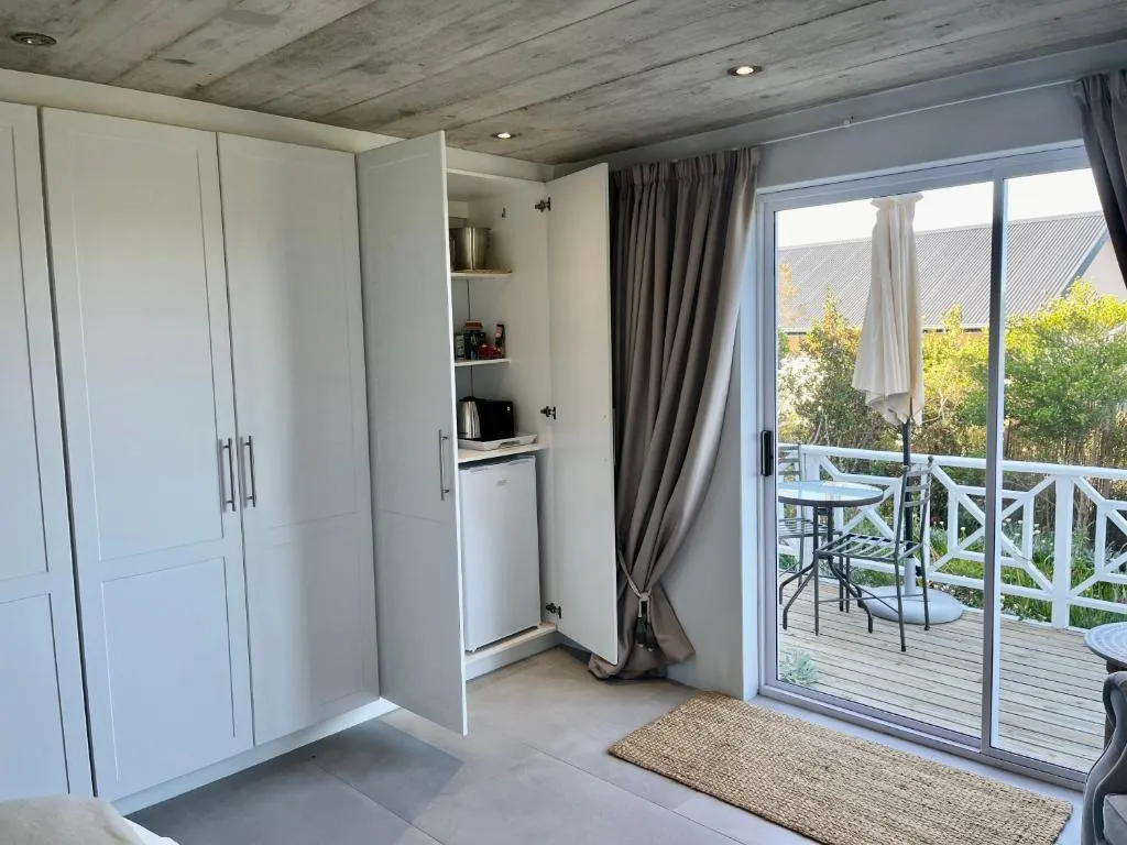 Built-in kitchenette with a kettle and bar fridge beside sliding doors onto a balcony