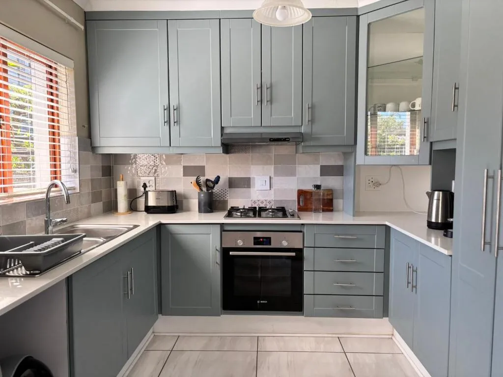 Kitchen with pale blue-grey cabinetry, gas hob and built-in oven