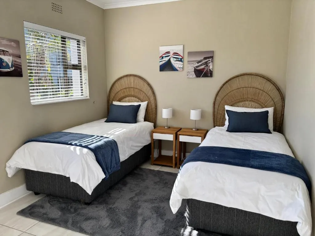 Twin bedroom with woven arch headboards and framed boat prints on the wall