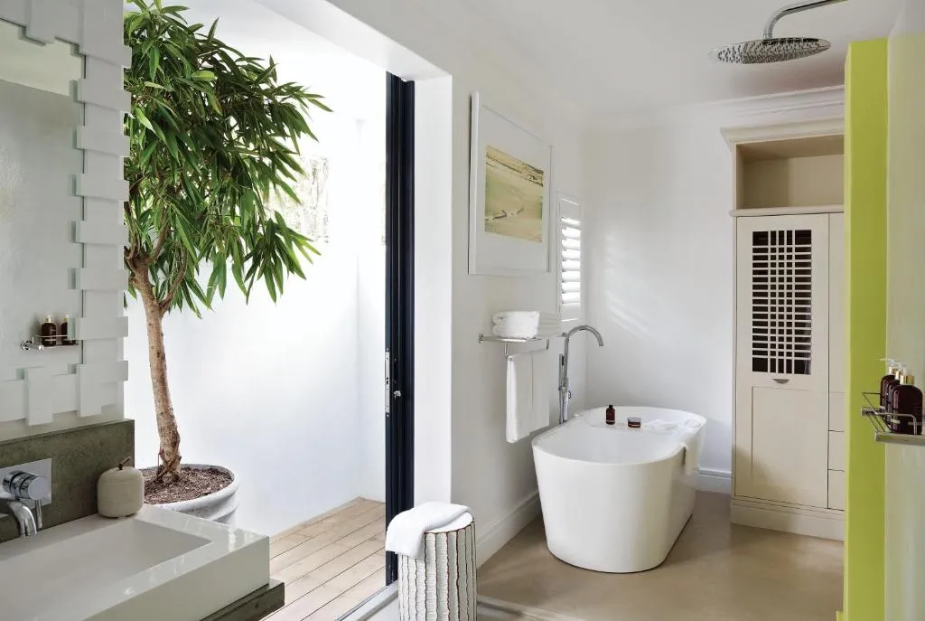 Bathroom with a freestanding tub, rain shower and an indoor tree beside the vanity