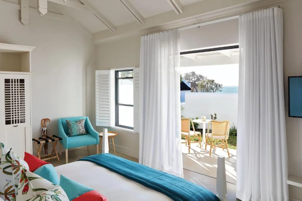 Bedroom with teal and red cushions, opening through curtained doors onto a private patio