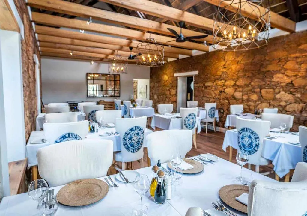 Dining room with exposed stone walls, wooden roof beams and wrought-iron chandeliers