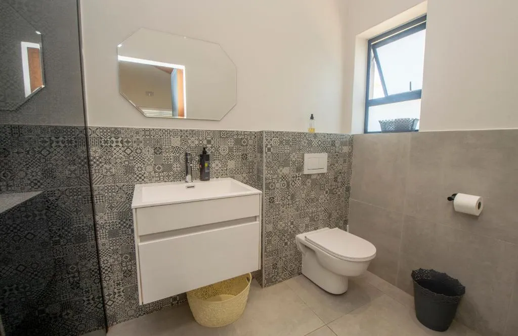 Bathroom with a white floating vanity, patterned tile splashback and a wall-hung toilet