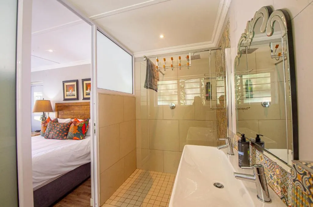 En-suite bathroom with a patterned tile shower, double vessel sink and adjoining bedroom