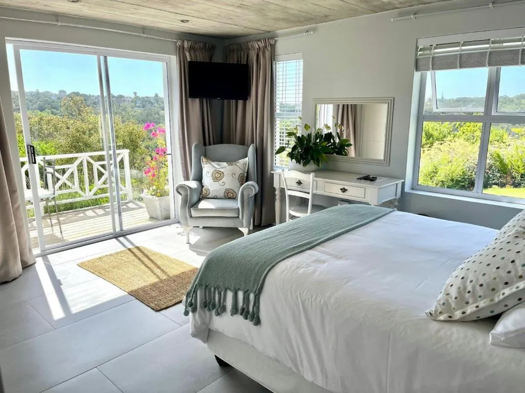 Bedroom with sliding doors onto a private balcony overlooking green hillside and rooftops