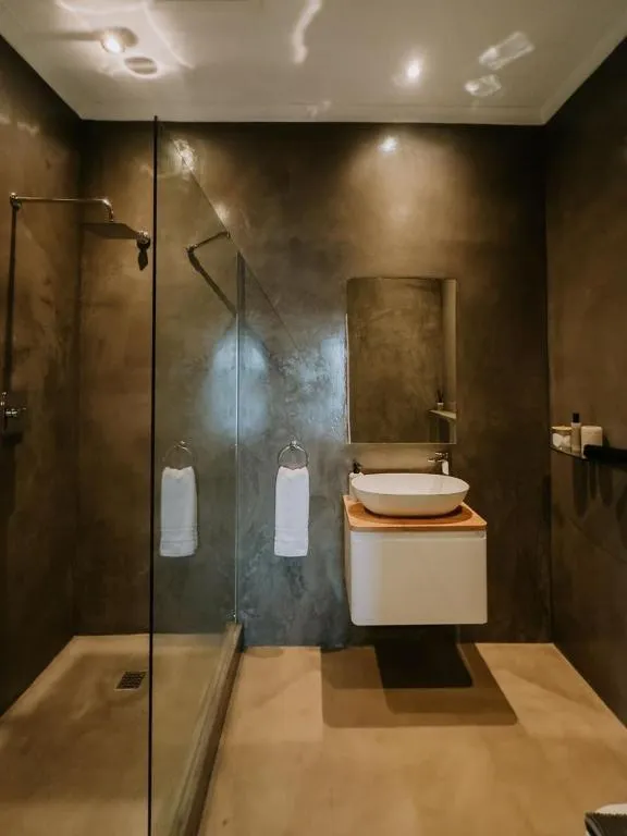 Bathroom with a walk-in glass shower, dark plaster walls and a freestanding vessel basin