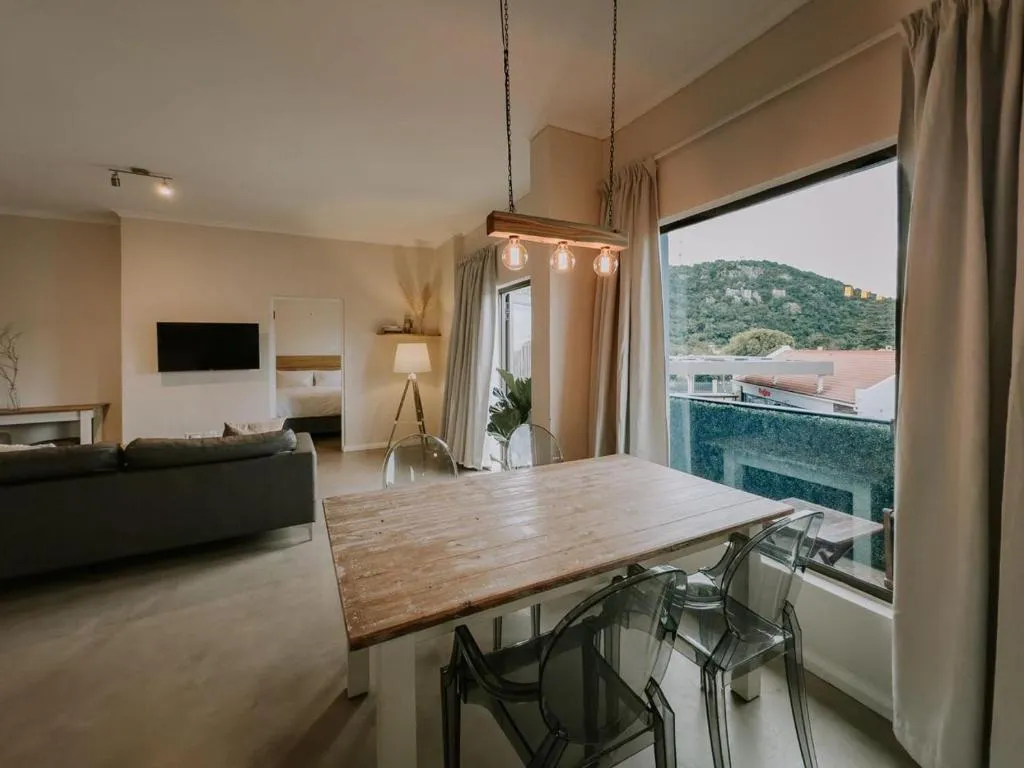 Dining table beside a large window looking out to a wooded hillside