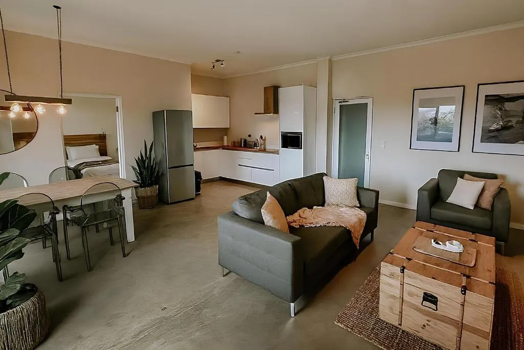 Open-plan living area with two-seater sofas, wall art and the kitchen visible beyond