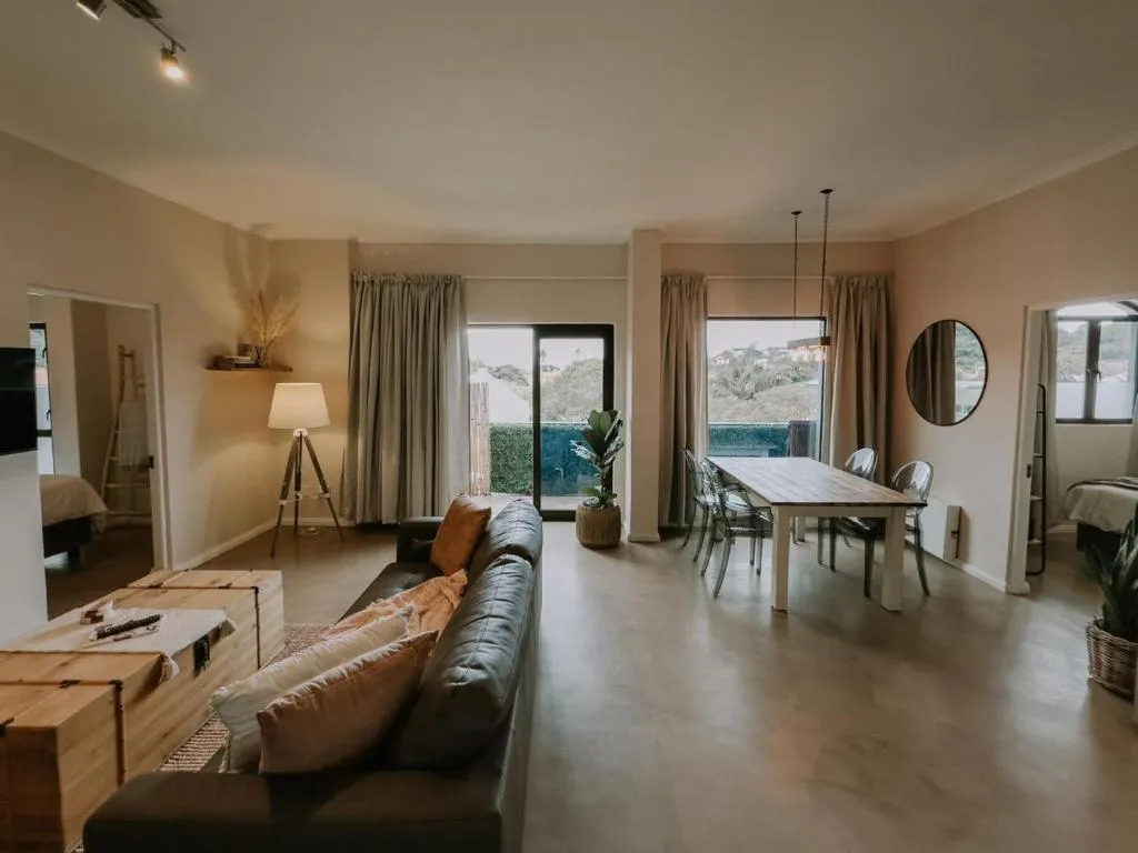 Living and dining area with a wooden table, tripod lamp and doors onto a balcony