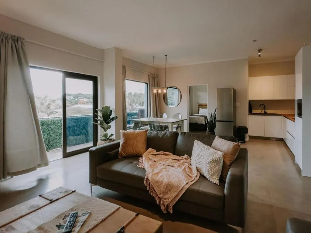 Open-plan kitchen with white cabinetry, breakfast bar and a glimpse of the bedroom beyond