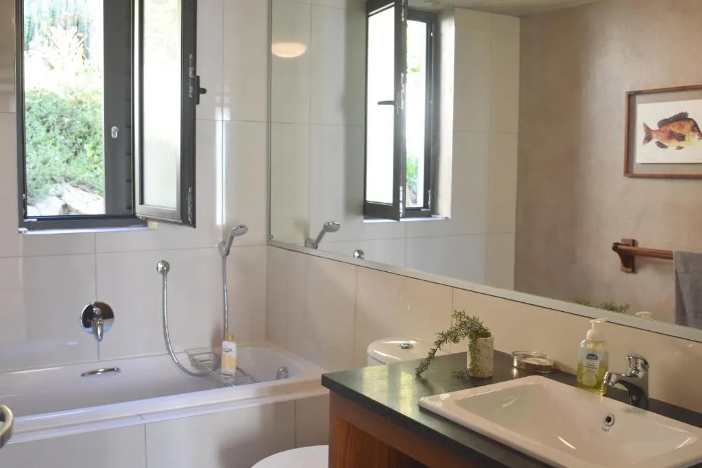 Bathroom with a built-in tub, walk-in shower and double casement windows open to the garden
