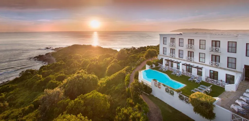 Aerial view of the hotel on a headland with its pool and gardens above the rocky shoreline