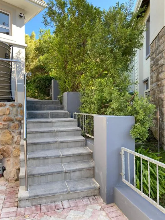 Stone steps lead up through landscaped shrubs to the entrance of the house