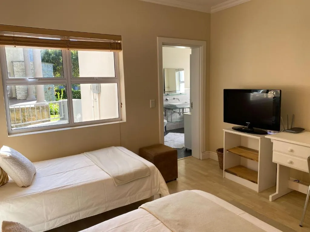 Twin bedroom with a wall-mounted TV and a doorway through to its own ensuite bathroom