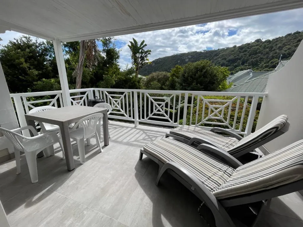 Covered balcony with dining table and loungers looking out to a forested hillside