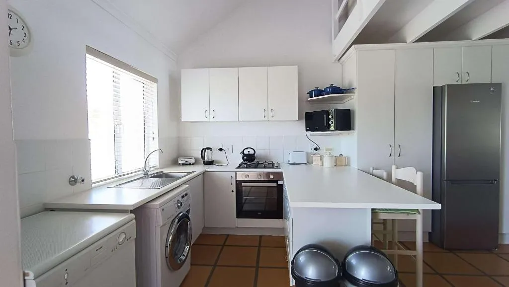 Kitchen with white cabinetry, gas stove, fridge and a small breakfast bar