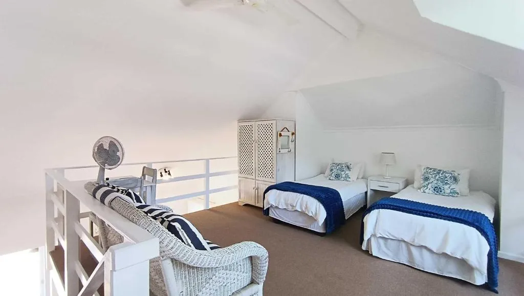 Loft bedroom under a sloped ceiling with two single beds in navy and white