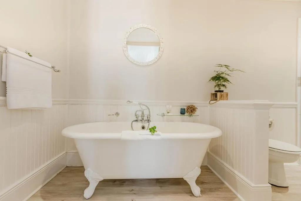 Bathroom with a freestanding clawfoot tub, round mirror and towel rail