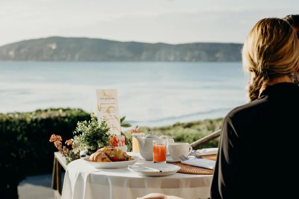 Outdoor breakfast table set for two with a headland and sea view beyond