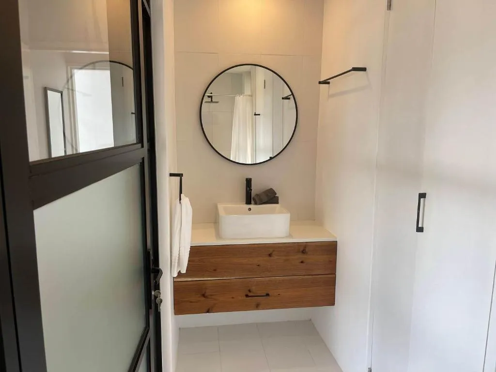 En-suite bathroom with round mirror, timber vanity and a walk-in glass shower