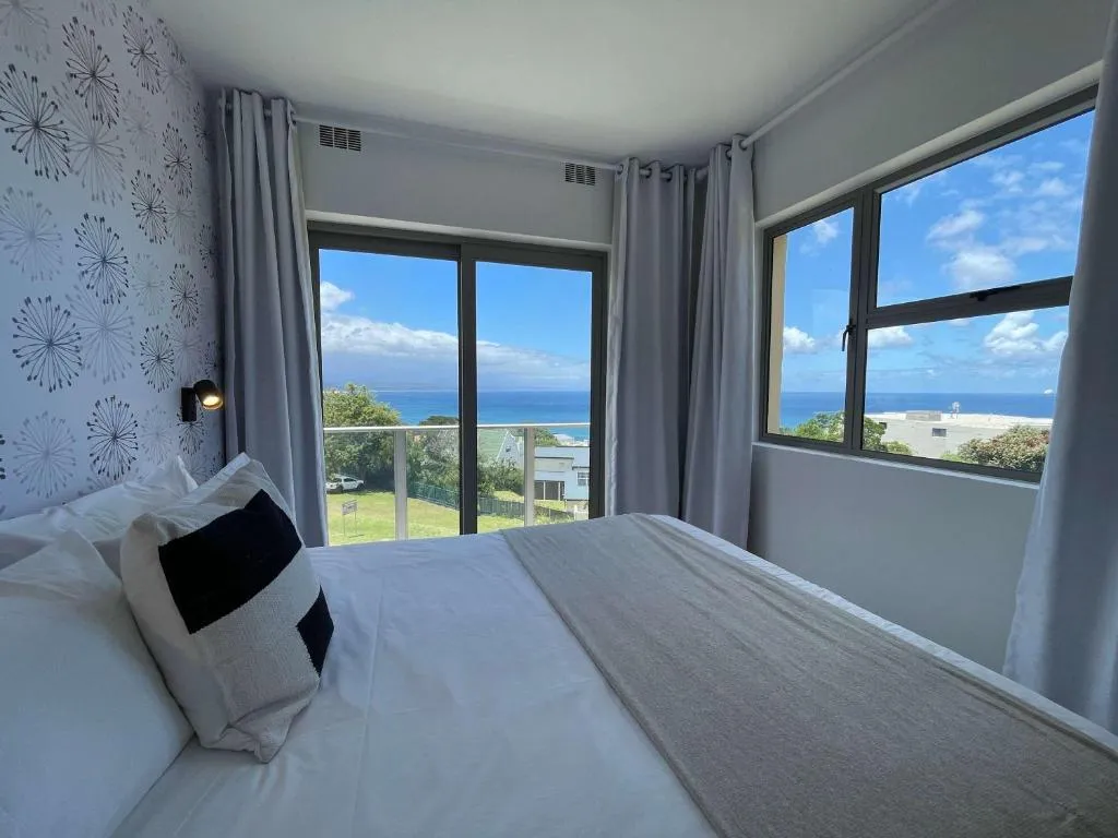 Bedroom with sliding door and window both framing an uninterrupted sea view