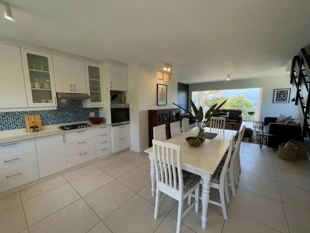 Open-plan kitchen with blue mosaic splashback and dining table seating eight