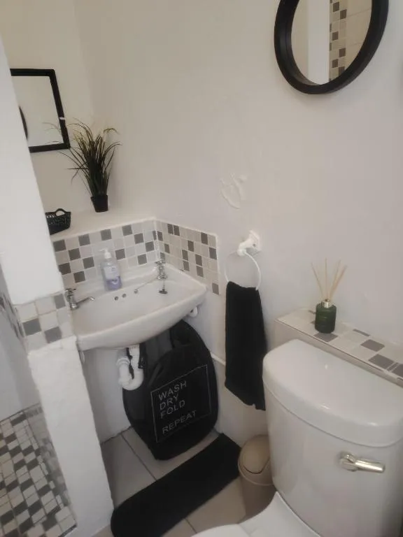 En-suite bathroom with a pedestal sink, black tile splashback and a laundry hamper